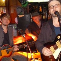 Eine Band, bestehend aus vier Musikern, steht auf der Bühne des Pubs