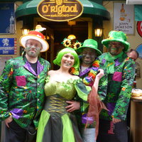 Vier Personen stehen vor dem Pub und tragen grüne Kostüme