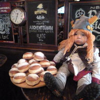 Ein kleiner Junge ist als Wikinger verkleidet, sitzt auf dem Tisch neben einem Teller voll Krapfen