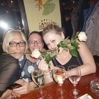 Drei Frauen halten eine Rose zwischen den Zähnen und lachen in die Kamera
